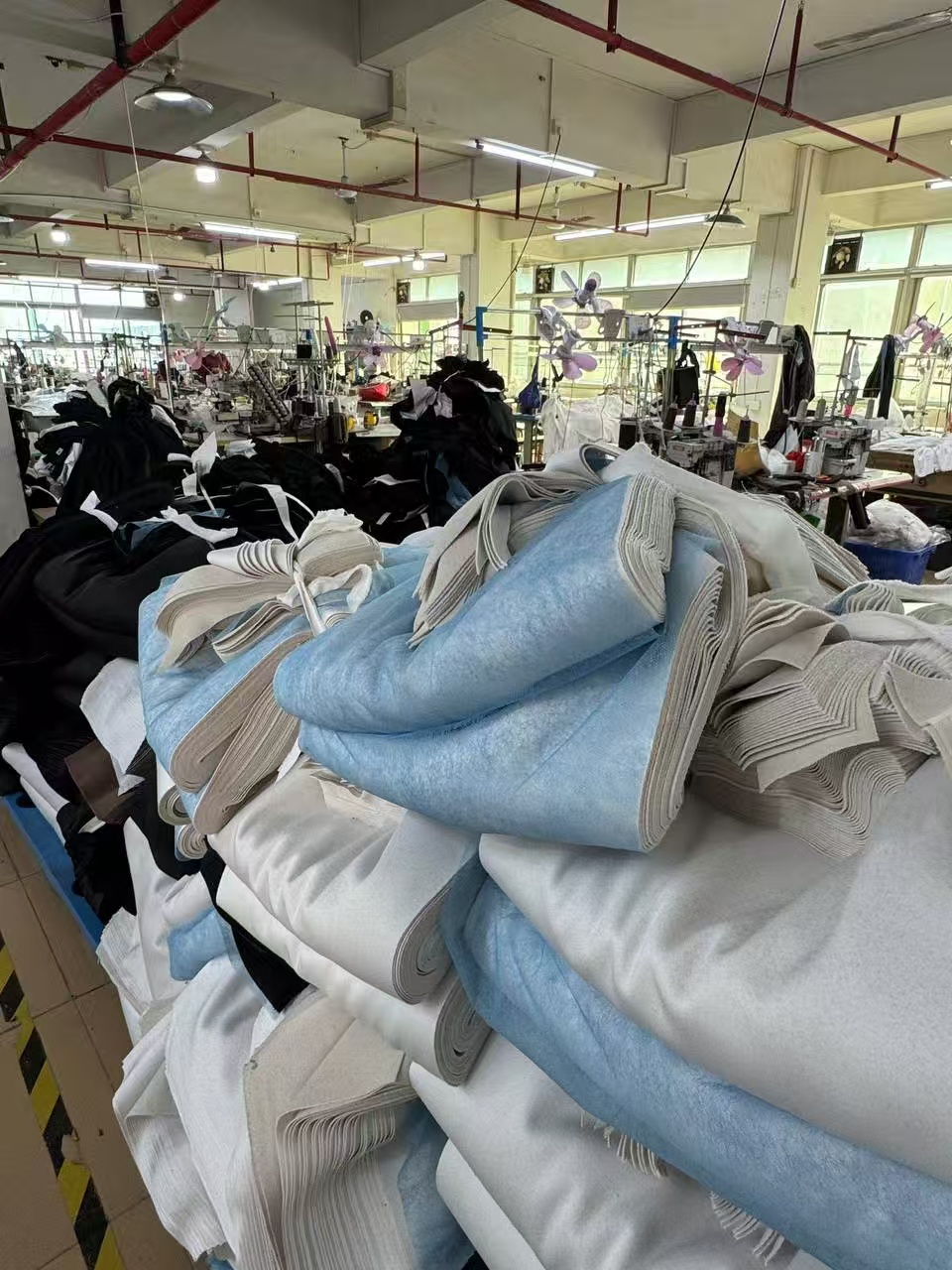 Sewing workshop floor with rows of machines and stacked fabric